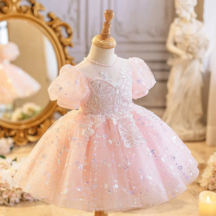 Pink toddler dress with puff sleeves and sequin floral embroidery on mannequin in elegant room