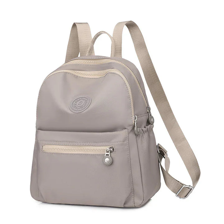 Beige small backpack with front zipper pocket and adjustable straps isolated on white