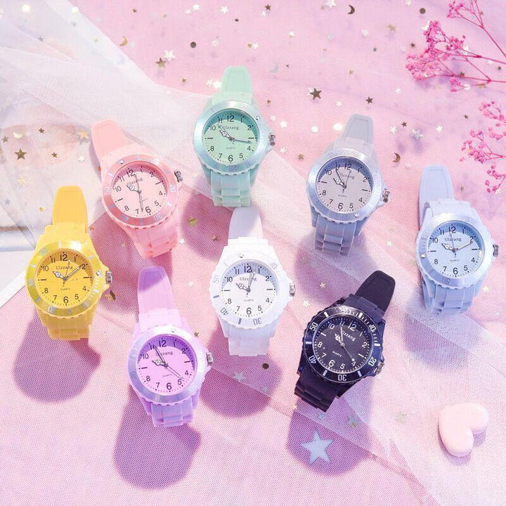 Colorful silicone wristwatches in pastel yellow, pink, purple, green, white, gray, and black on pink starry fabric background