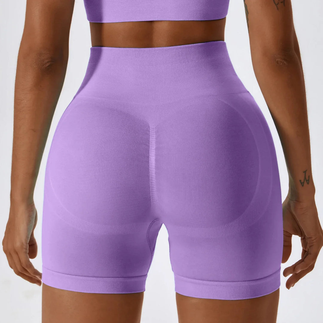 Woman in seamless high-waisted purple workout shorts and crop top, back view