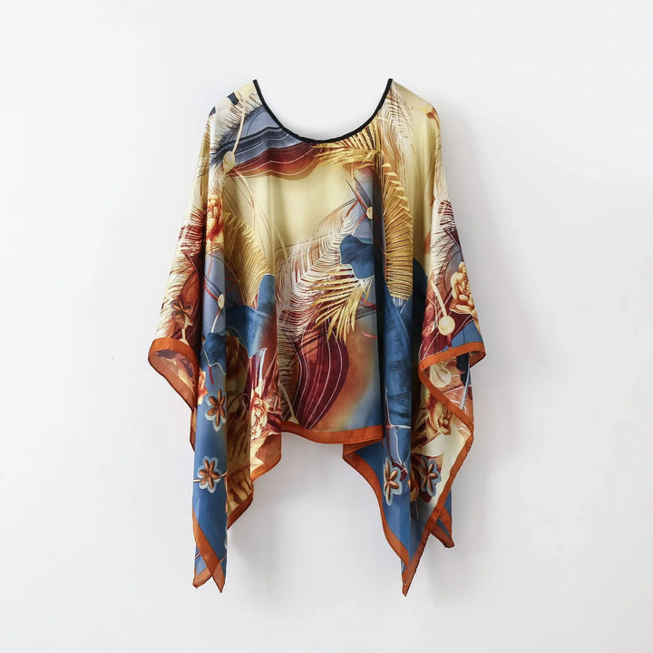 Colorful women's poncho with tropical floral and leaf print in blue, brown, and beige