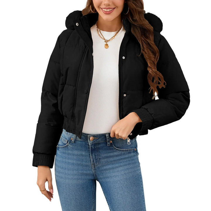 Woman wearing black cropped puffer jacket with hood, white top, and blue jeans