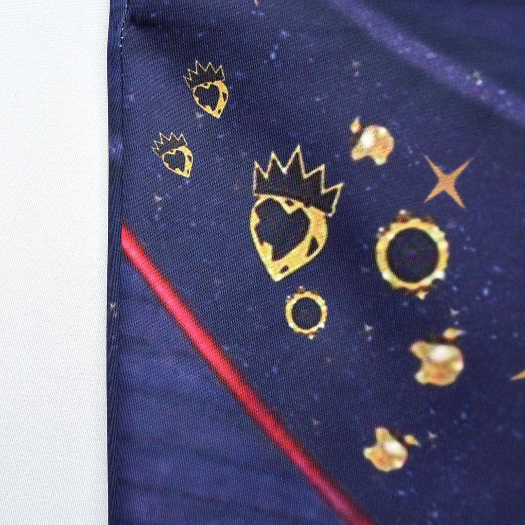 Close-up of navy blue fabric with gold heart crowned symbols and star-like patterns and red diagonal line