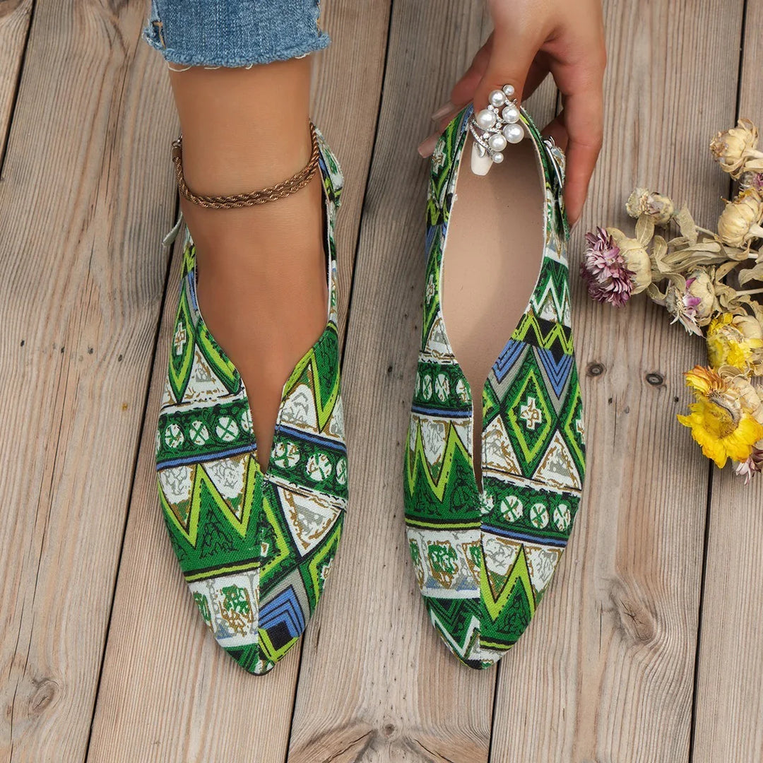 Pair of green patterned pointed flats with floral and geometric designs on wooden floor, one worn with anklet
