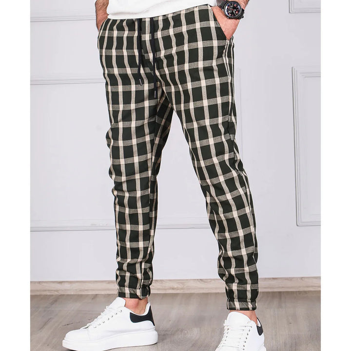 Men's black and white checkered casual jogger pants with white sneakers and wristwatch