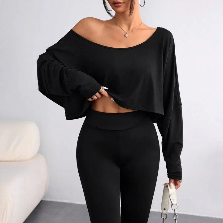 Woman wearing black off-shoulder cropped top and high-waisted black leggings holding a purse strap