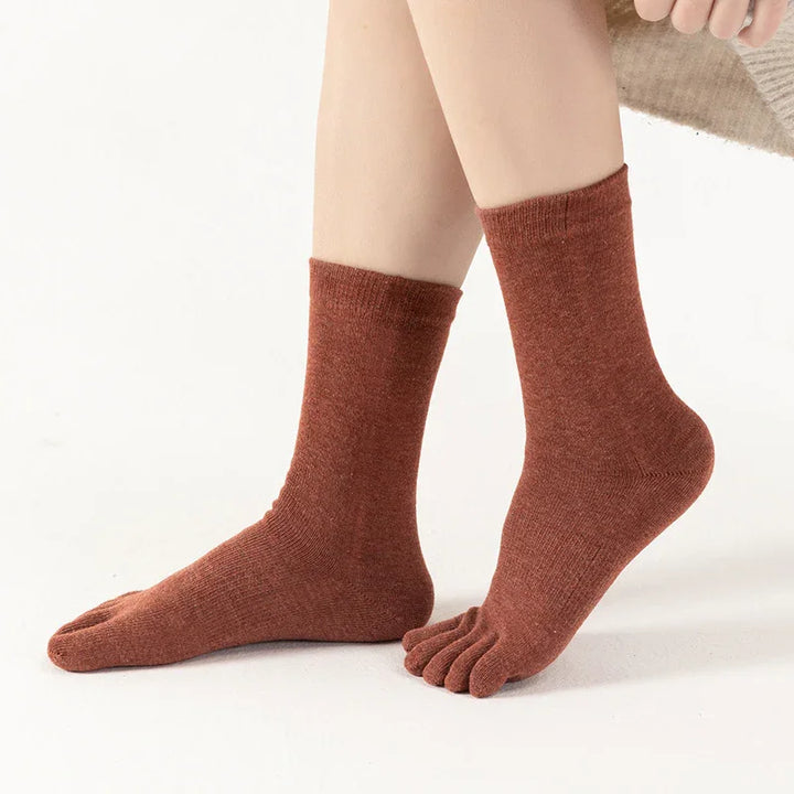 Brown toe socks on feet with separate compartments for each toe, cozy knit fabric