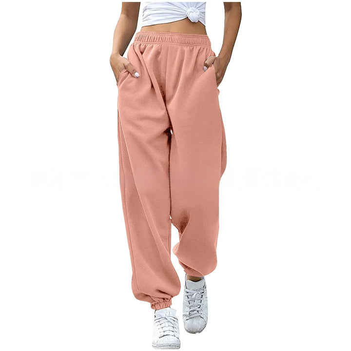 Woman wearing pink elastic-waist jogger pants with pockets and white sneakers, styled with a knotted white crop top