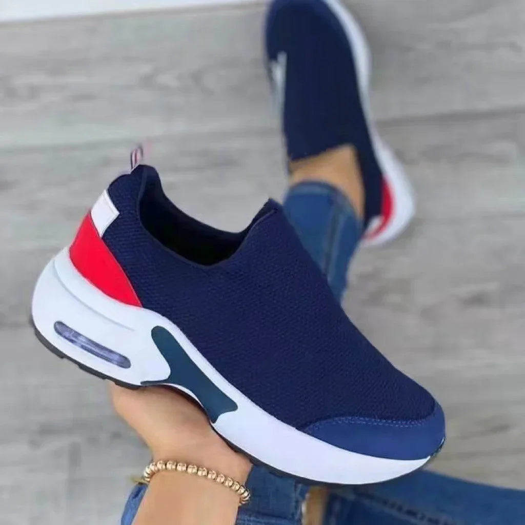 Close-up of navy blue slip-on athletic sneaker with white sole and red heel detail