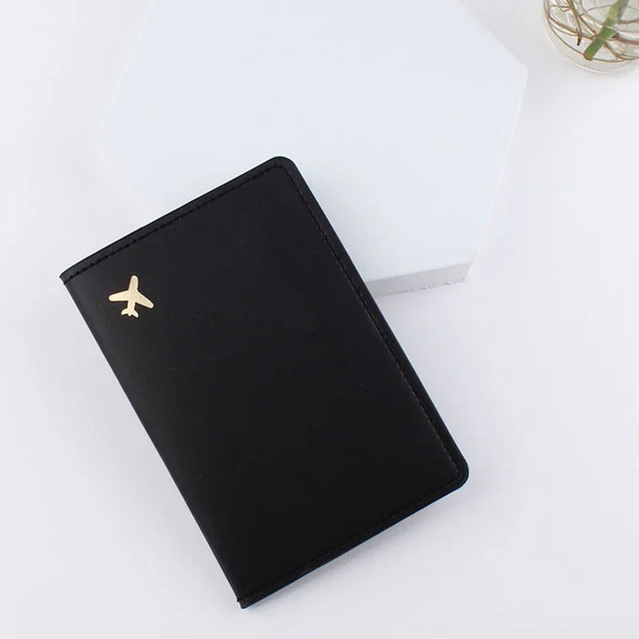 Black travel passport holder with gold airplane icon on white surface and hexagonal stand