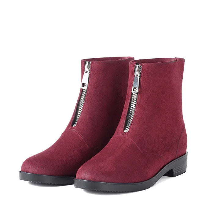 Red suede ankle boots with front silver zipper and low black heel on white background