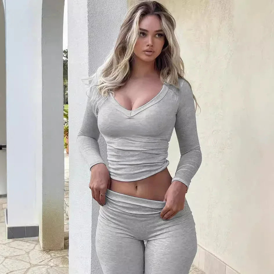 Woman in fitted light gray long-sleeve top and leggings outdoors near white pillars