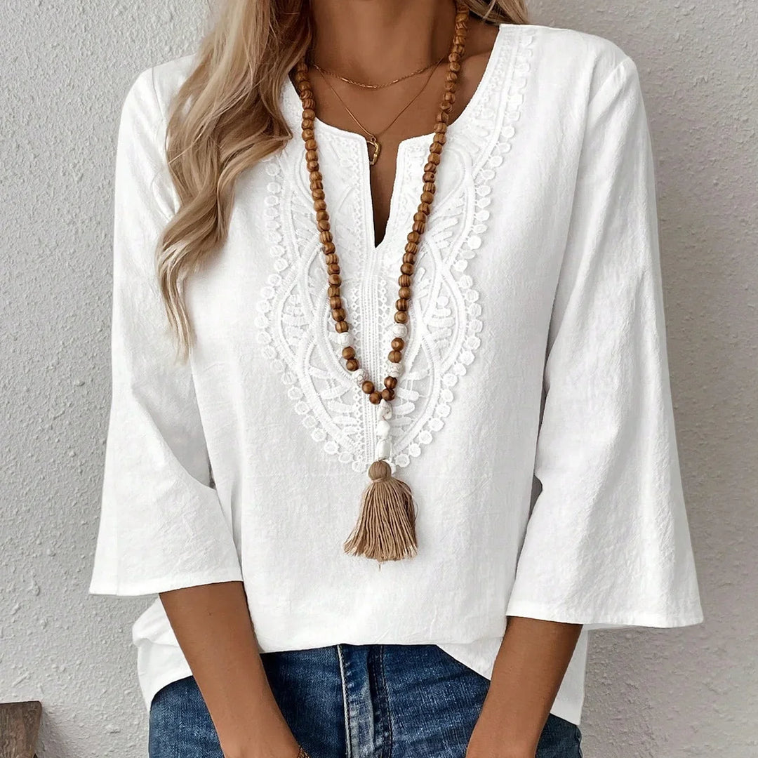 Woman wearing white embroidered boho blouse with 3/4 sleeves and wooden bead tassel necklace