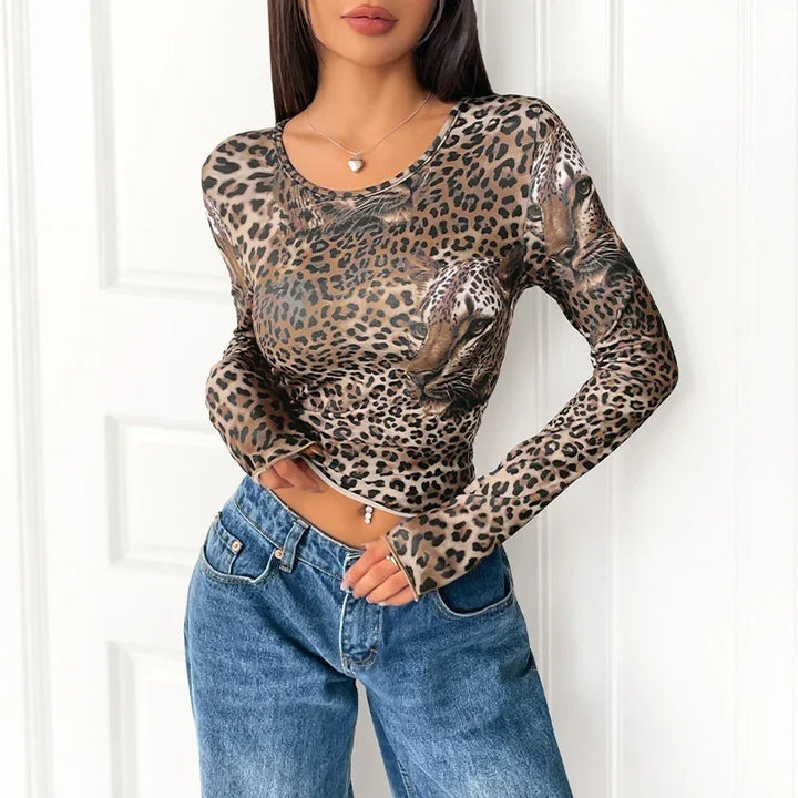 Woman wearing leopard print long sleeve top with big cat face design and blue jeans