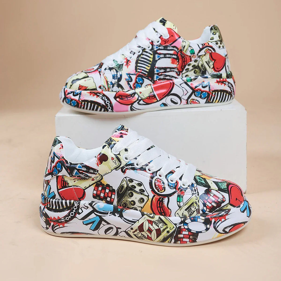 Colorful graffiti print sneakers with white laces displayed on white block against beige background