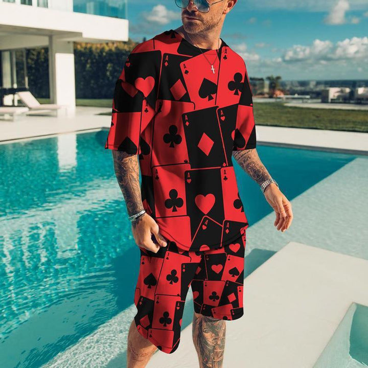 Man wearing red and black playing card print outfit standing by a modern pool under blue sky