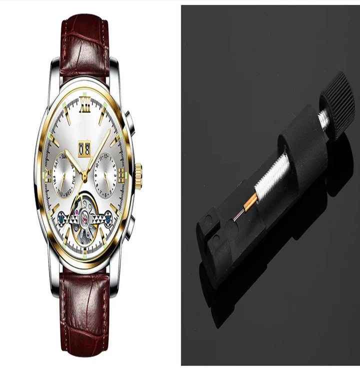 Luxury wristwatch with gold accents and brown leather strap next to a small watch gear mechanism