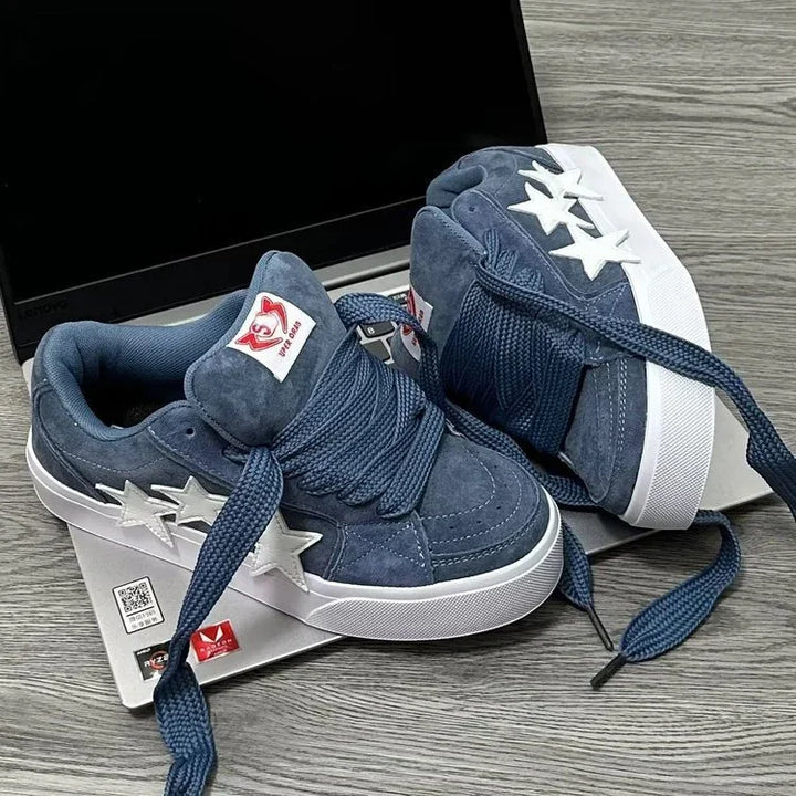 Blue suede sneakers with white star accents and thick laces on a laptop keyboard
