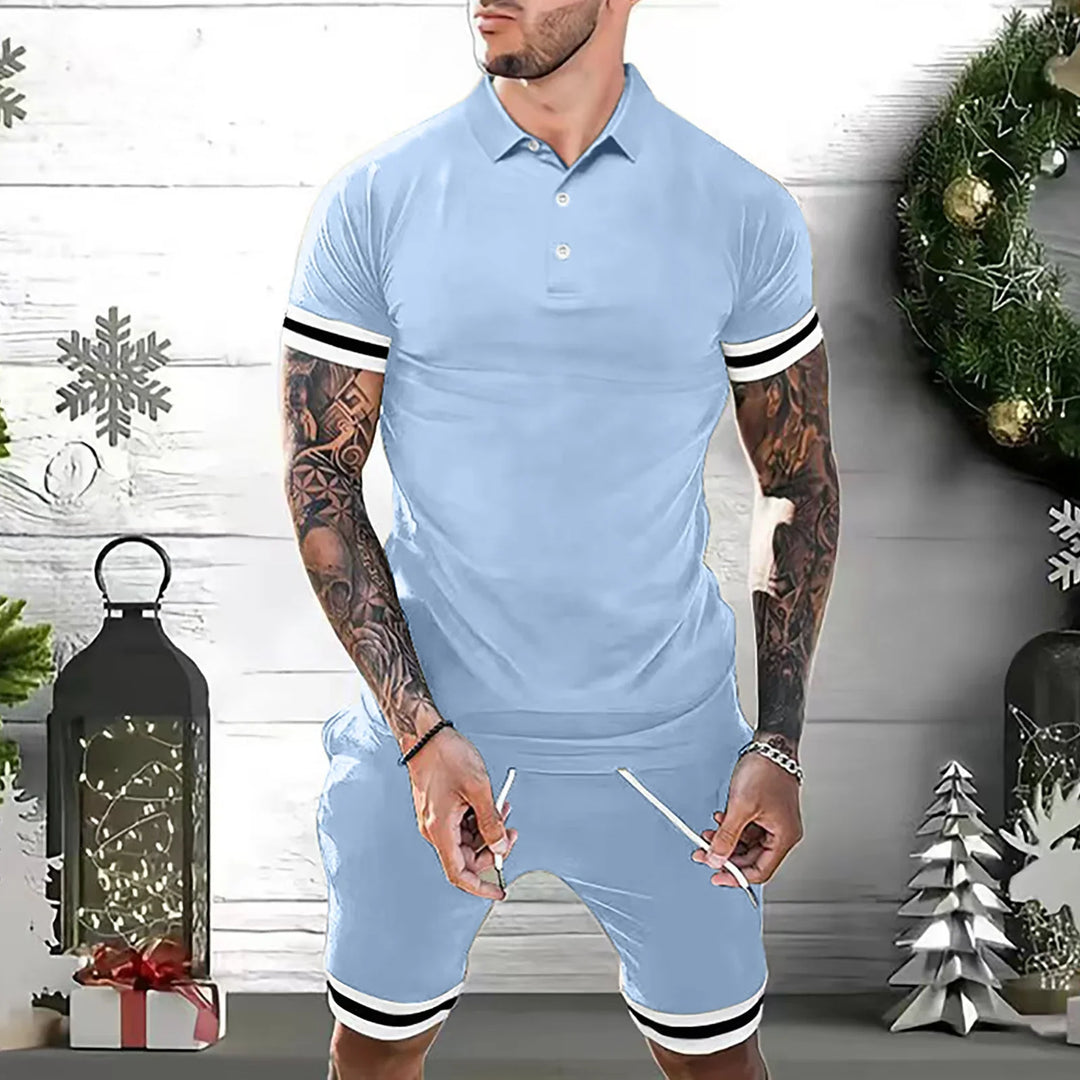 Tattooed man wearing light blue polo shirt and shorts with black and white striped cuffs in festive room