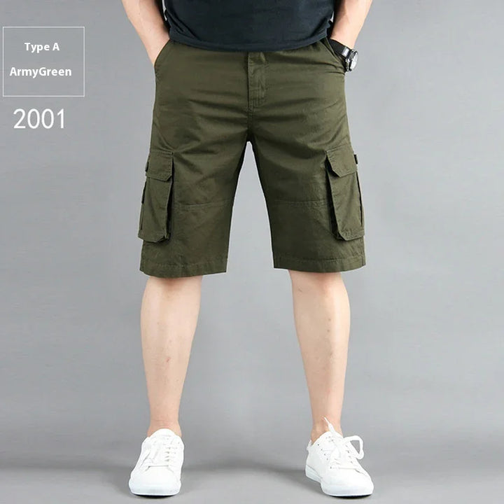 Man wearing army green cargo shorts and white sneakers against gray background