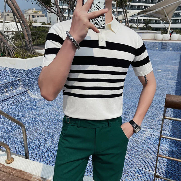 Man wearing white and black striped polo shirt and green pants by empty blue tiled pool