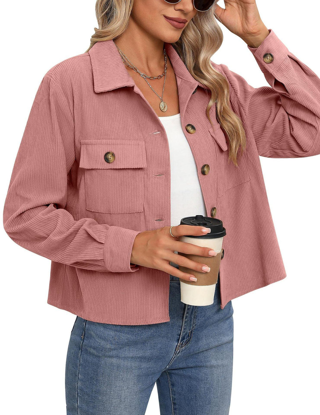 Woman wearing pink corduroy button-up jacket with breast pockets, blue jeans, holding a takeaway coffee cup