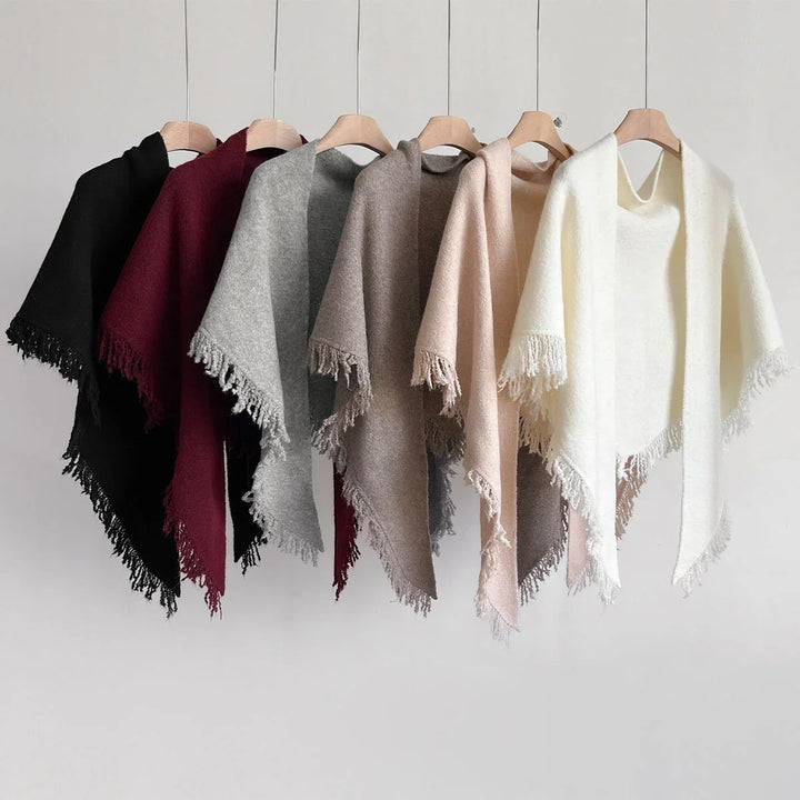 Soft wool fringe shawls in black, burgundy, grey, brown, beige, and white colors hanging on wooden hangers