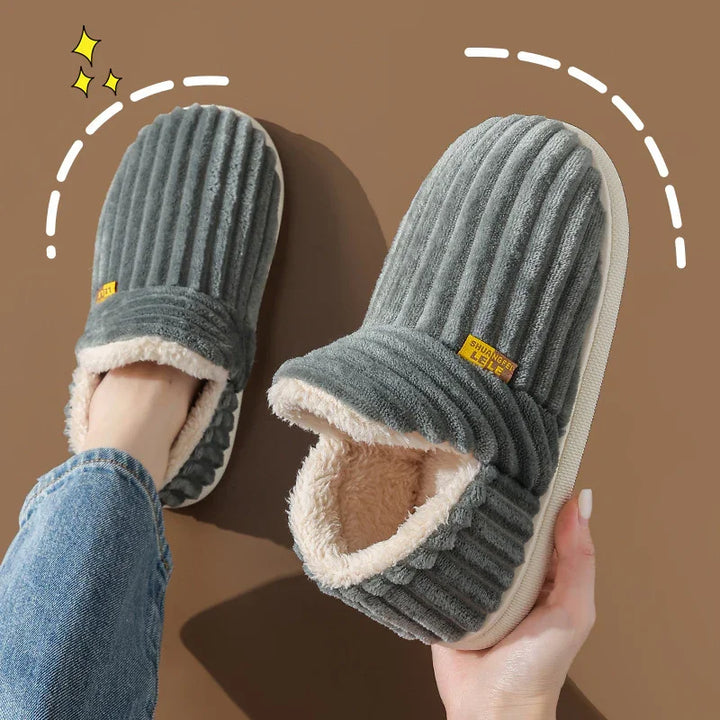 Gray ribbed plush indoor slippers with soft beige fleece lining worn by person in jeans