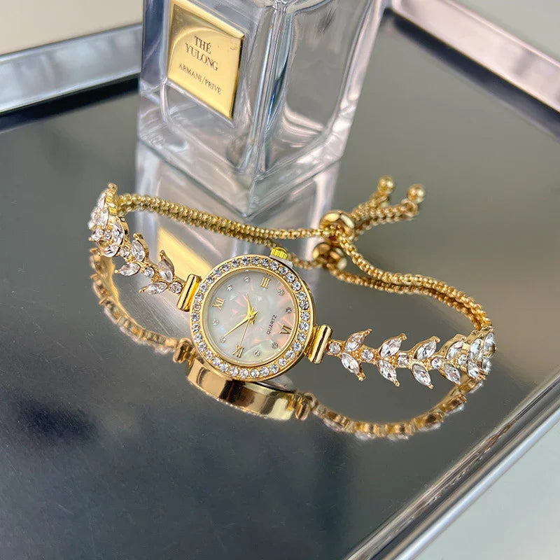Elegant gold-tone bracelet watch with crystal accents and mother-of-pearl dial on reflective surface