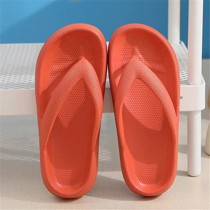 Pair of orange textured rubber flip-flop sandals on white chair with blue background