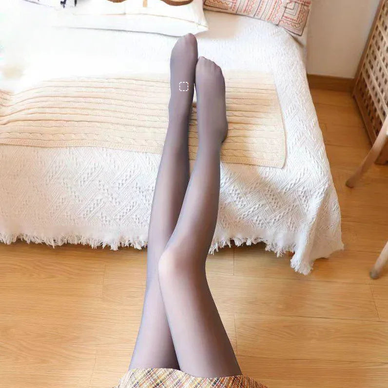 legs wearing sheer grey pantyhose on bed with white textured blanket and wooden floor