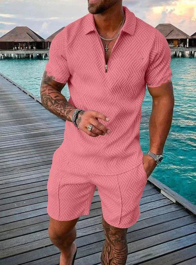 Man wearing pink textured short-sleeve polo shirt and shorts on wooden pier over turquoise water