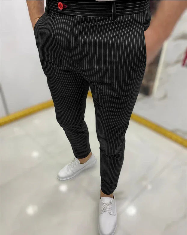 Man wearing black pinstripe pants with red button detail paired with white casual shoes on glossy floor
