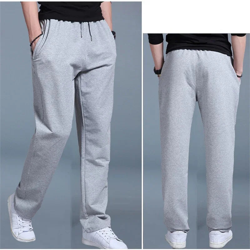 Front and back views of man wearing light gray sweatpants with elastic waistband and white sneakers