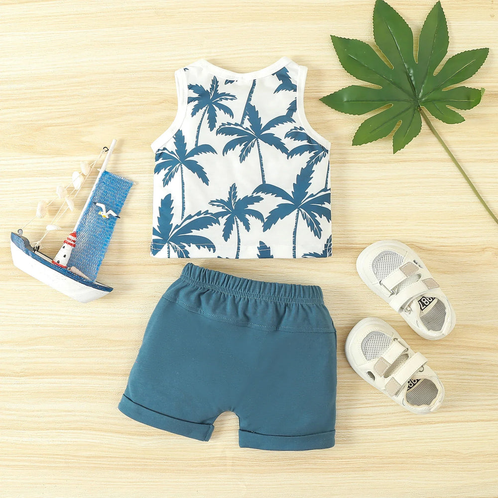 Baby boy summer outfit with white palm tree print tank top and teal shorts on wooden background