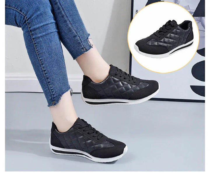 Black quilted casual sneakers with white soles worn with blue jeans on light grey floor