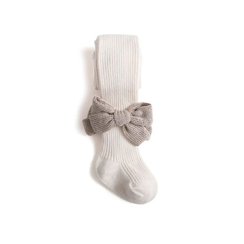Cream ribbed baby tights with large knitted taupe bow on white background