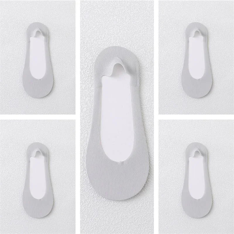 Multiple white no-show ankle socks with ribbed texture on a textured white background