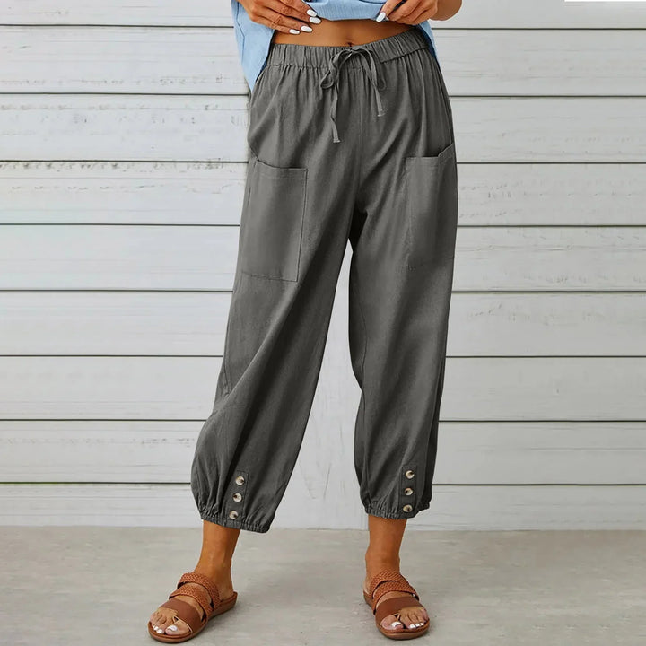 Woman wearing gray casual drawstring pants with front pockets and buttoned cuffs, brown woven sandals