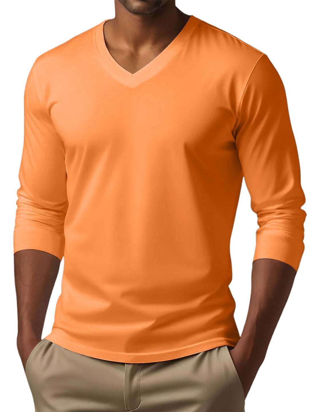 Man wearing orange V-neck long sleeve shirt with hands in beige pants pockets
