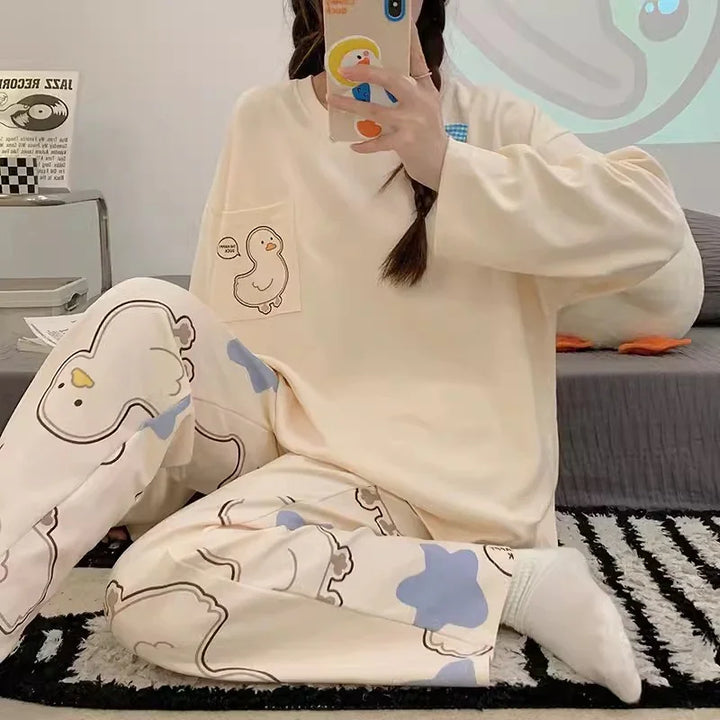 Person wearing cream-colored duck print loungewear with matching sweatshirt and pants sitting on black and white rug indoors
