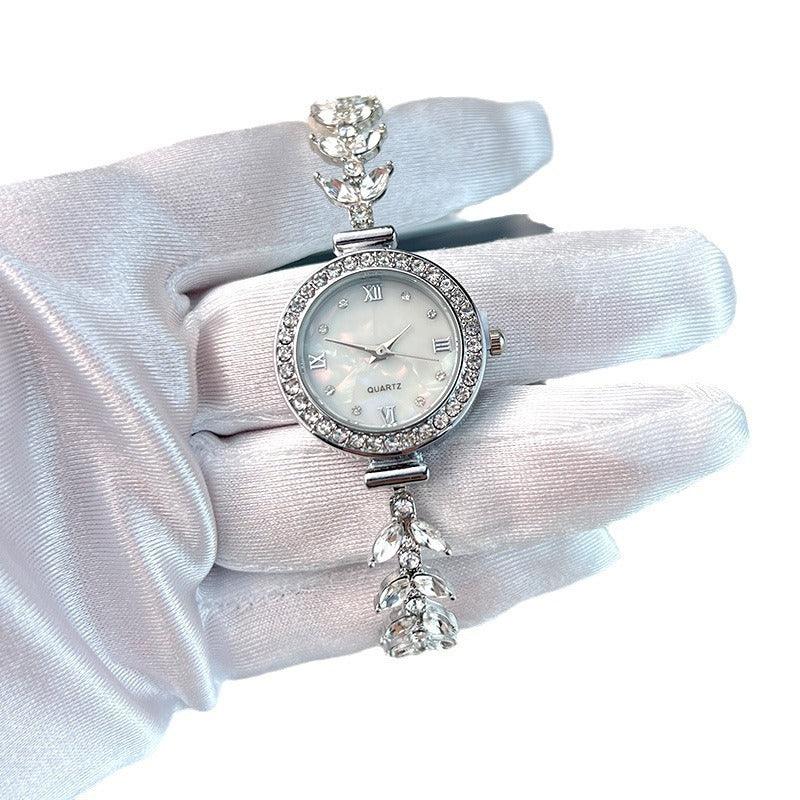 Elegant silver quartz wristwatch with crystal bezel and leaf-shaped crystal bracelet held in white glove