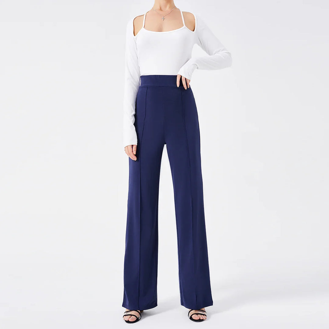 Woman wearing white cold-shoulder long sleeve top with navy high-waisted wide-leg pants and black sandals