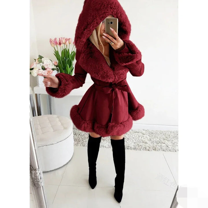 Woman wearing a burgundy faux fur trimmed hooded coat with a waist tie and black knee-high boots