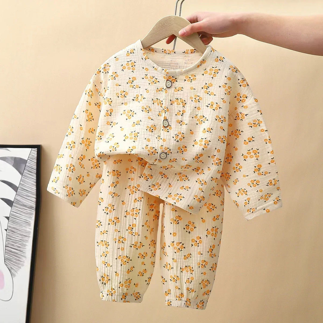 Hand holding baby floral pajamas set with yellow flowers on beige background