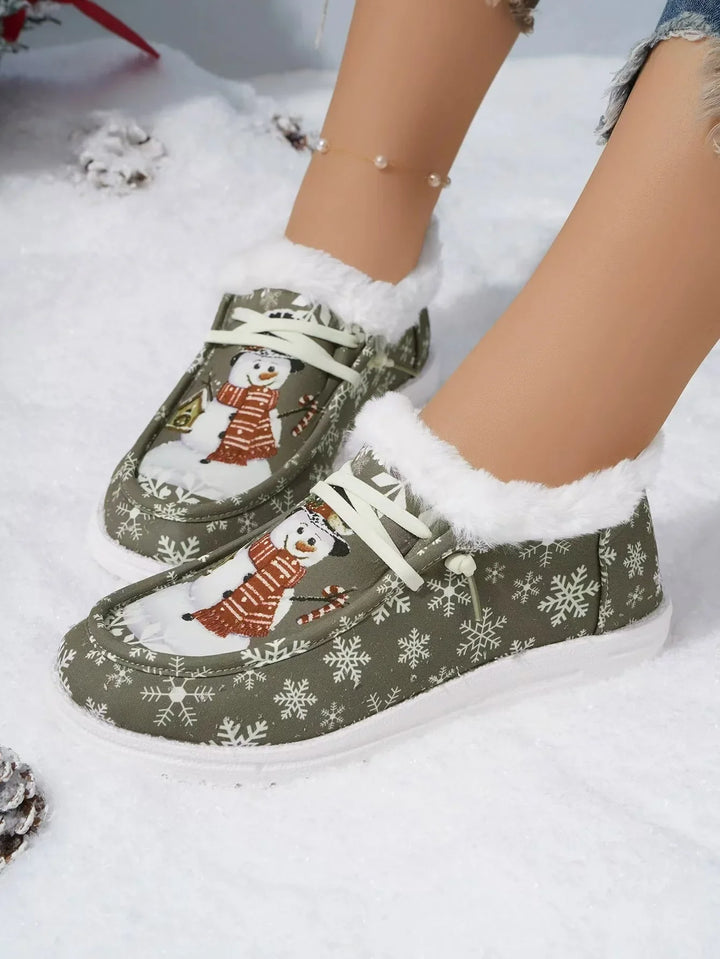 Green winter slippers with snowman and snowflake design, white fur lining, worn on snow