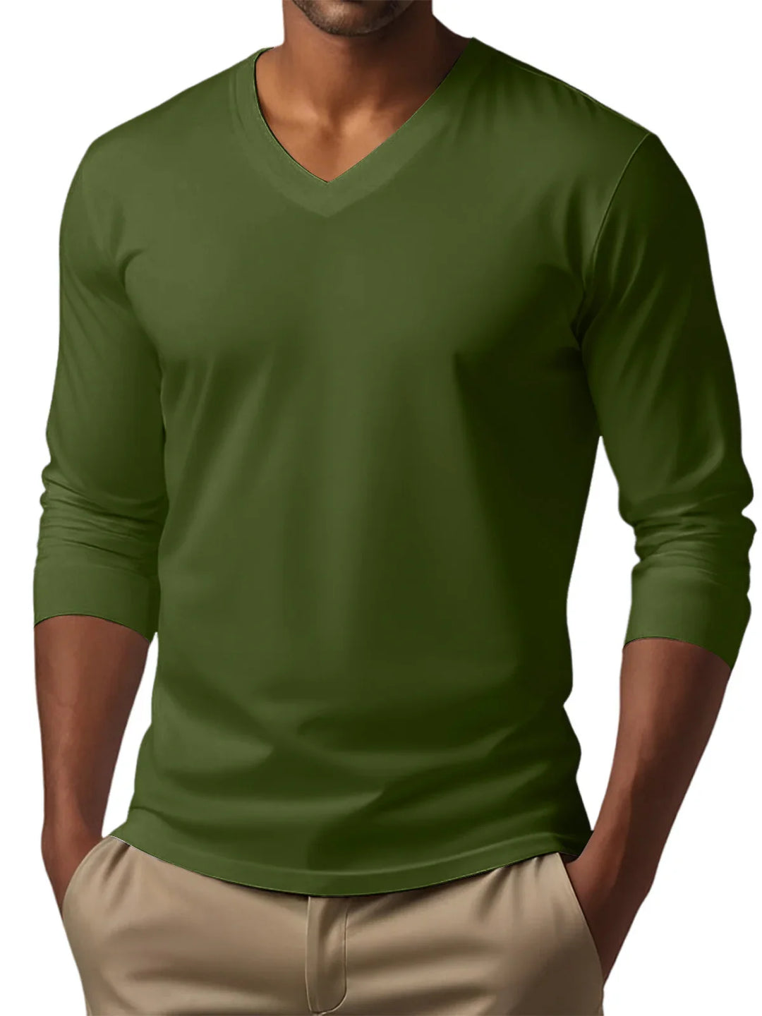 Man wearing olive green long sleeve V-neck shirt with beige pants, hands in pockets