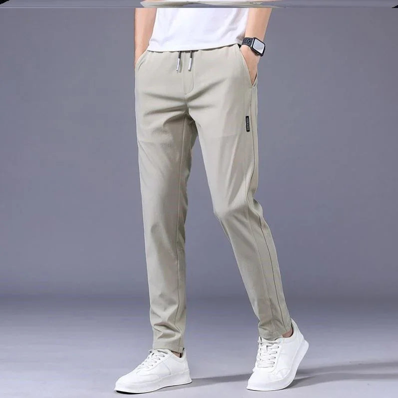 Man wearing beige casual slim-fit pants with drawstring waist and white sneakers