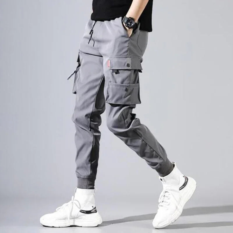 Person wearing gray cargo jogger pants with multiple pockets and white chunky sneakers