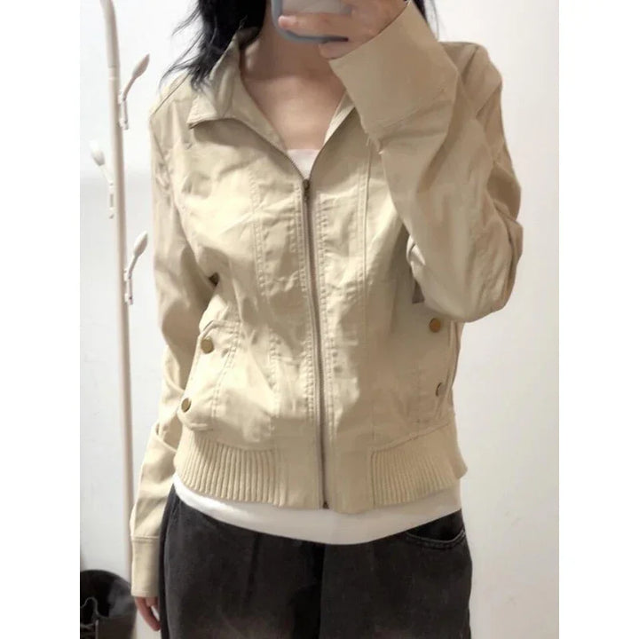 Woman wearing beige zip-up jacket with ribbed hem and brass button details, casual outfit